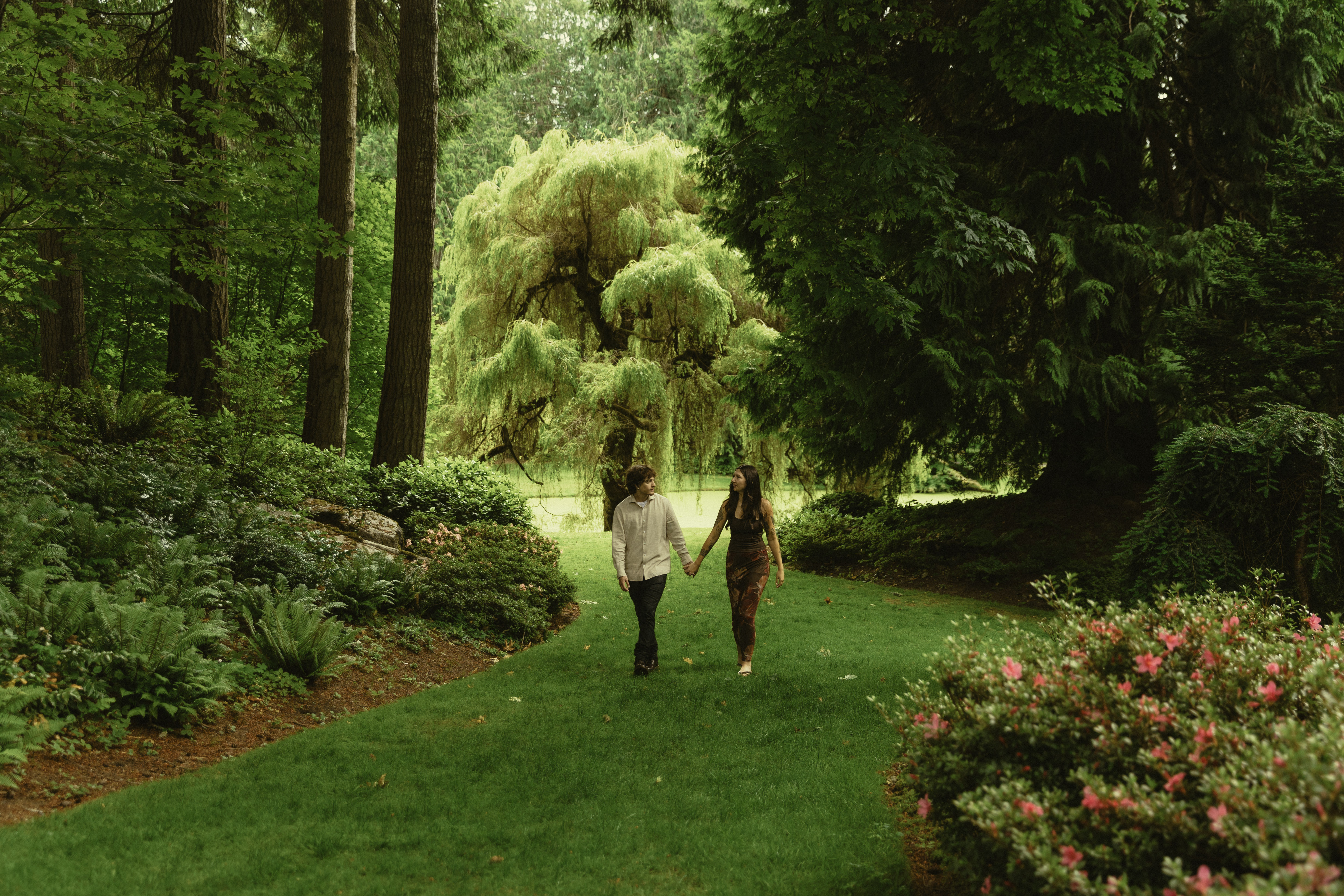 Shelby and Hamza walking hand in hand through a garden