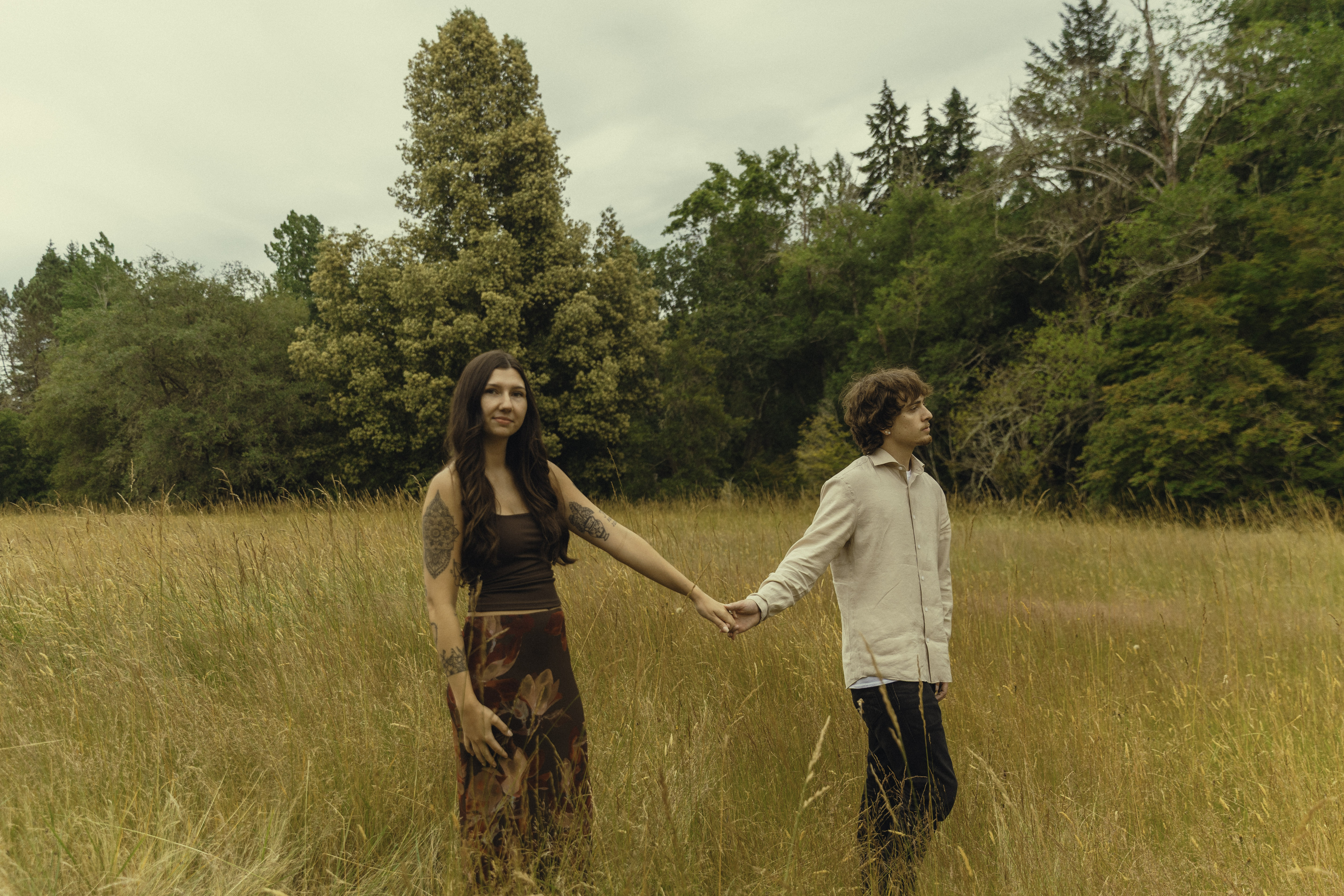 Shelby and Hamza holding hands in a tall grass field