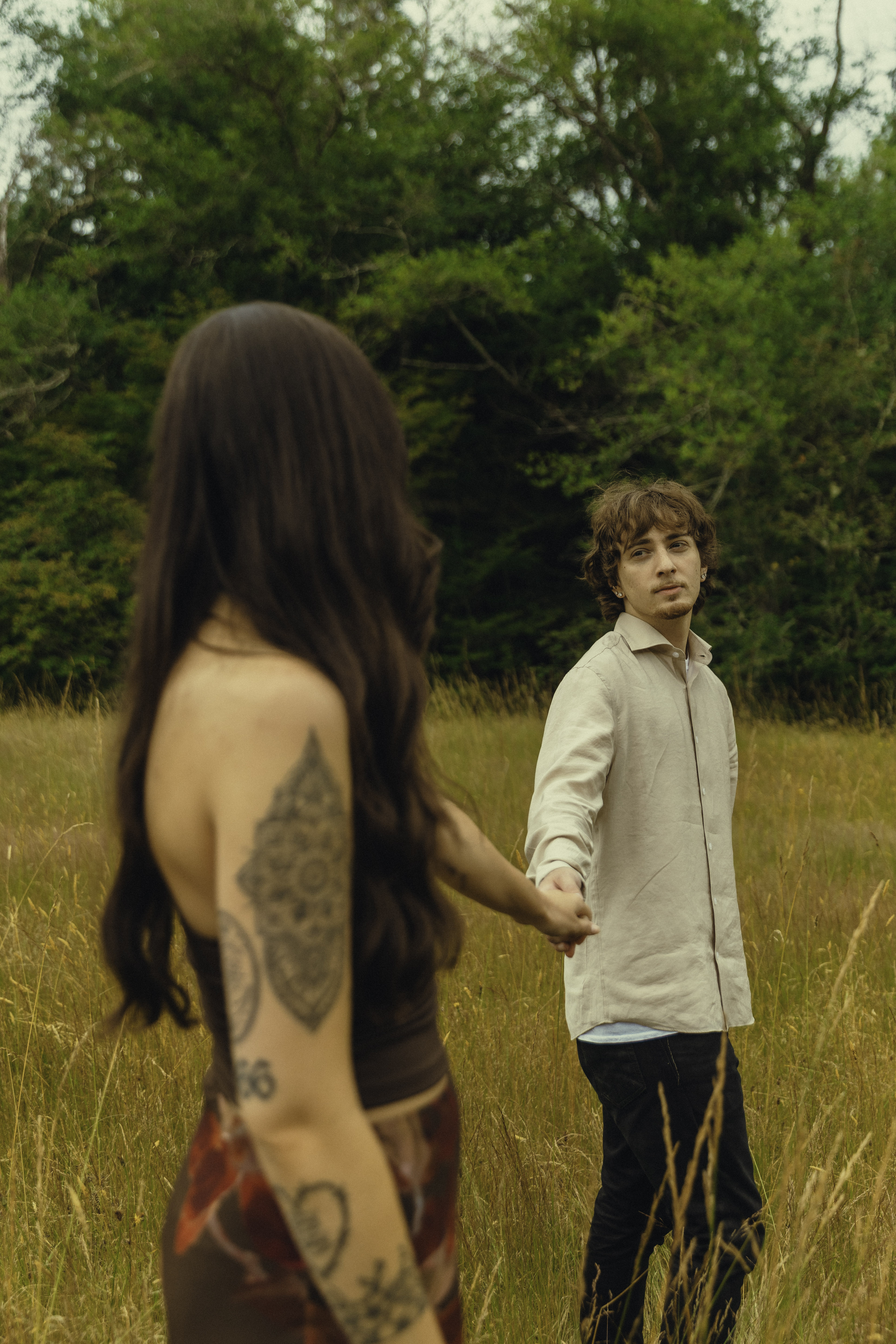 Hamza looking back at Shelby as they hold hands in the field