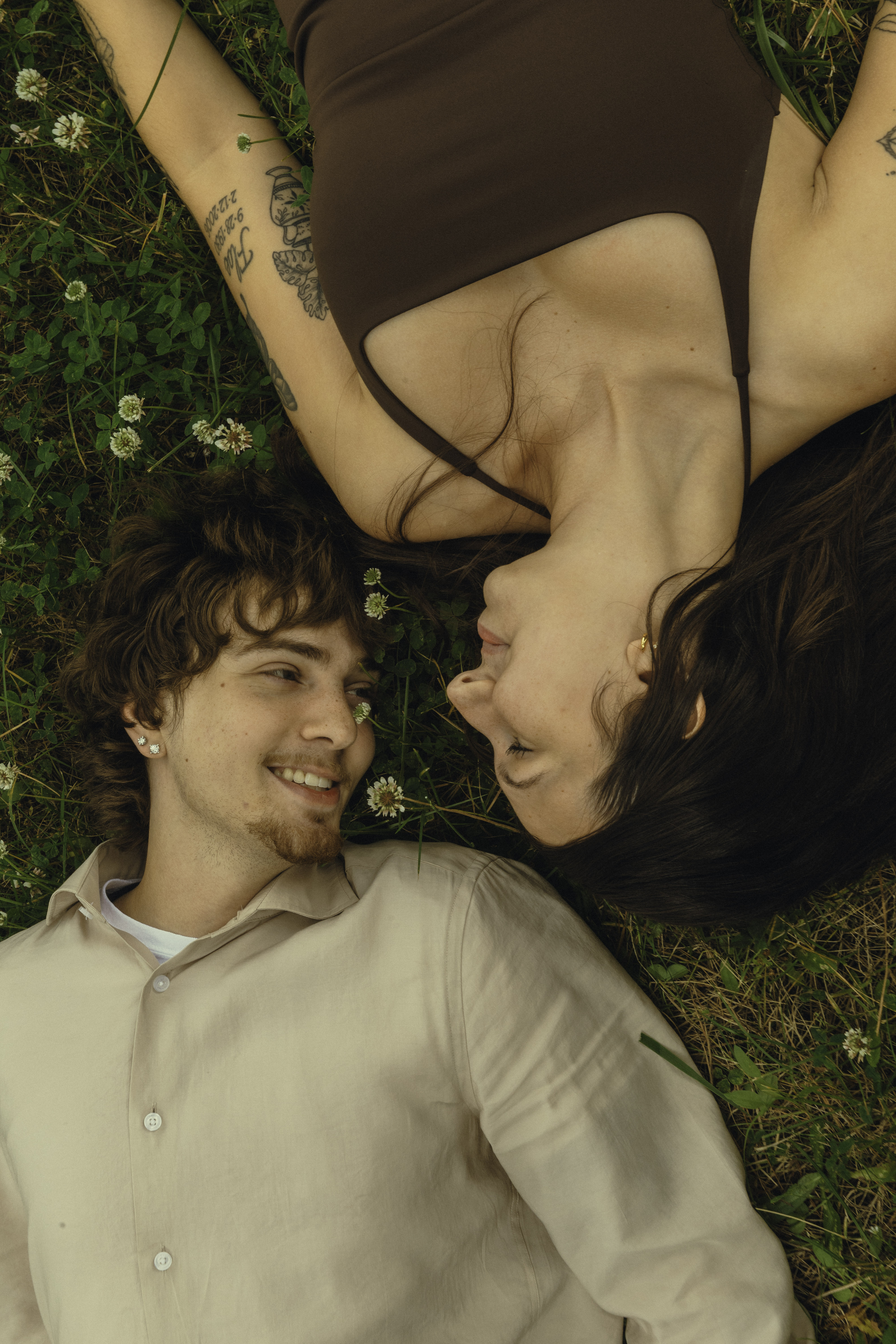 Shelby and Hamza lying in the clover, smiling at each other